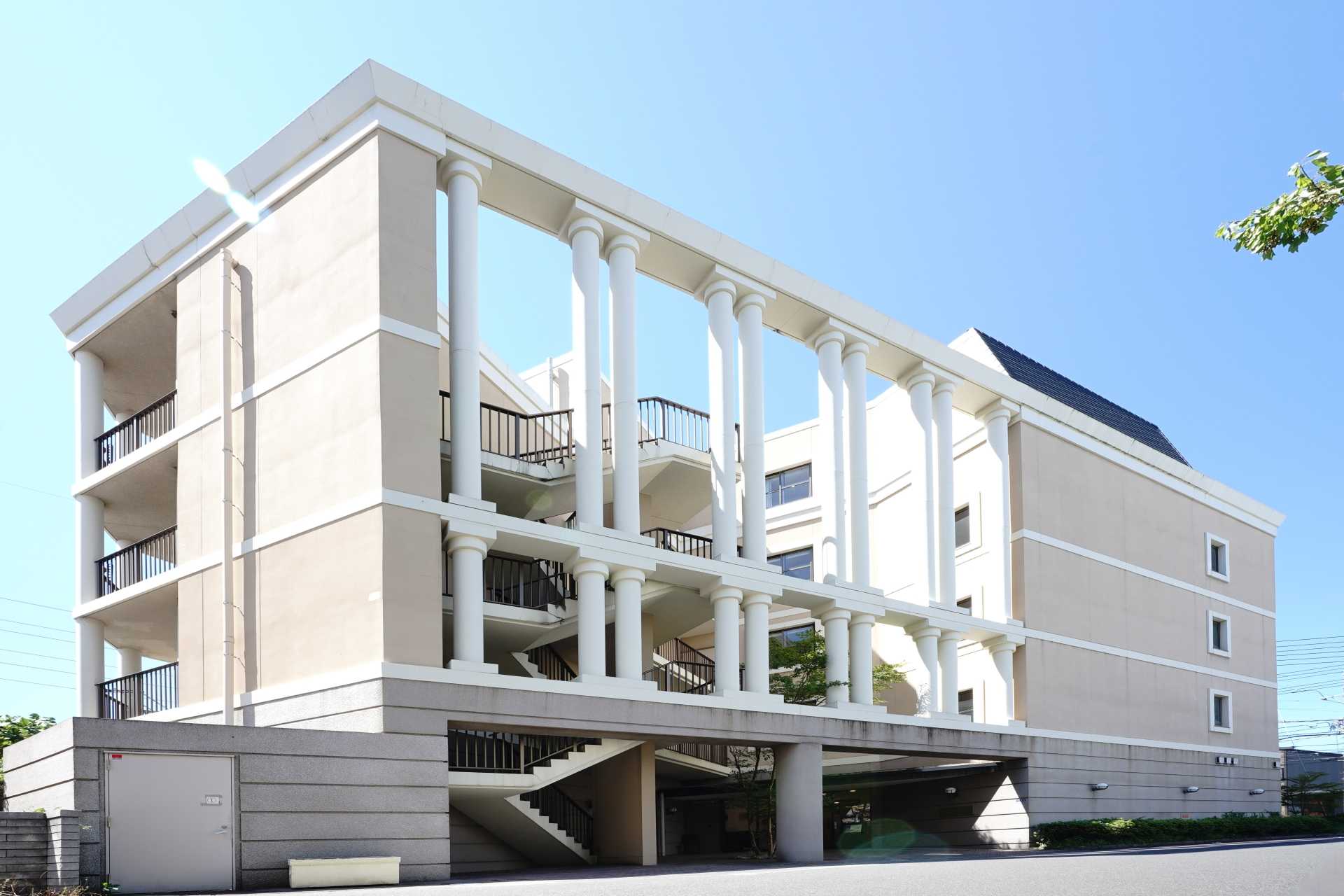 白を基調とした介護施設の建物外観。柱と大きな開口が特徴の4階建て。